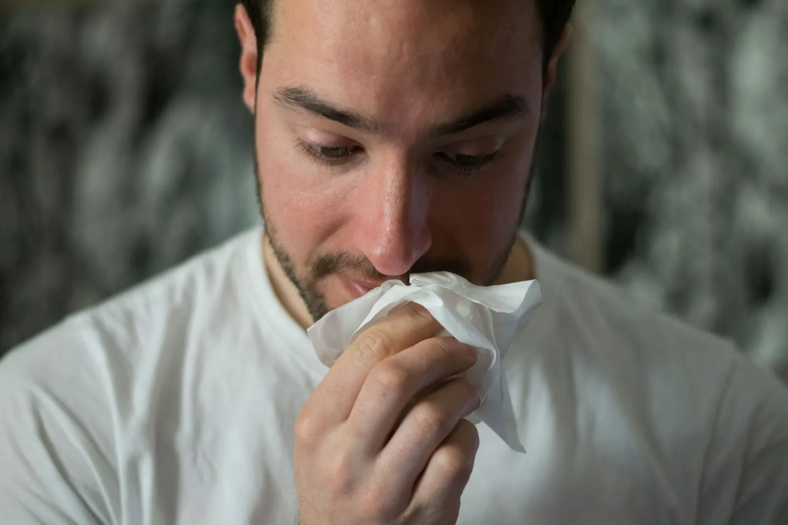 Gripe: homem com sintomas de influenza assoando o nariz com um lenço